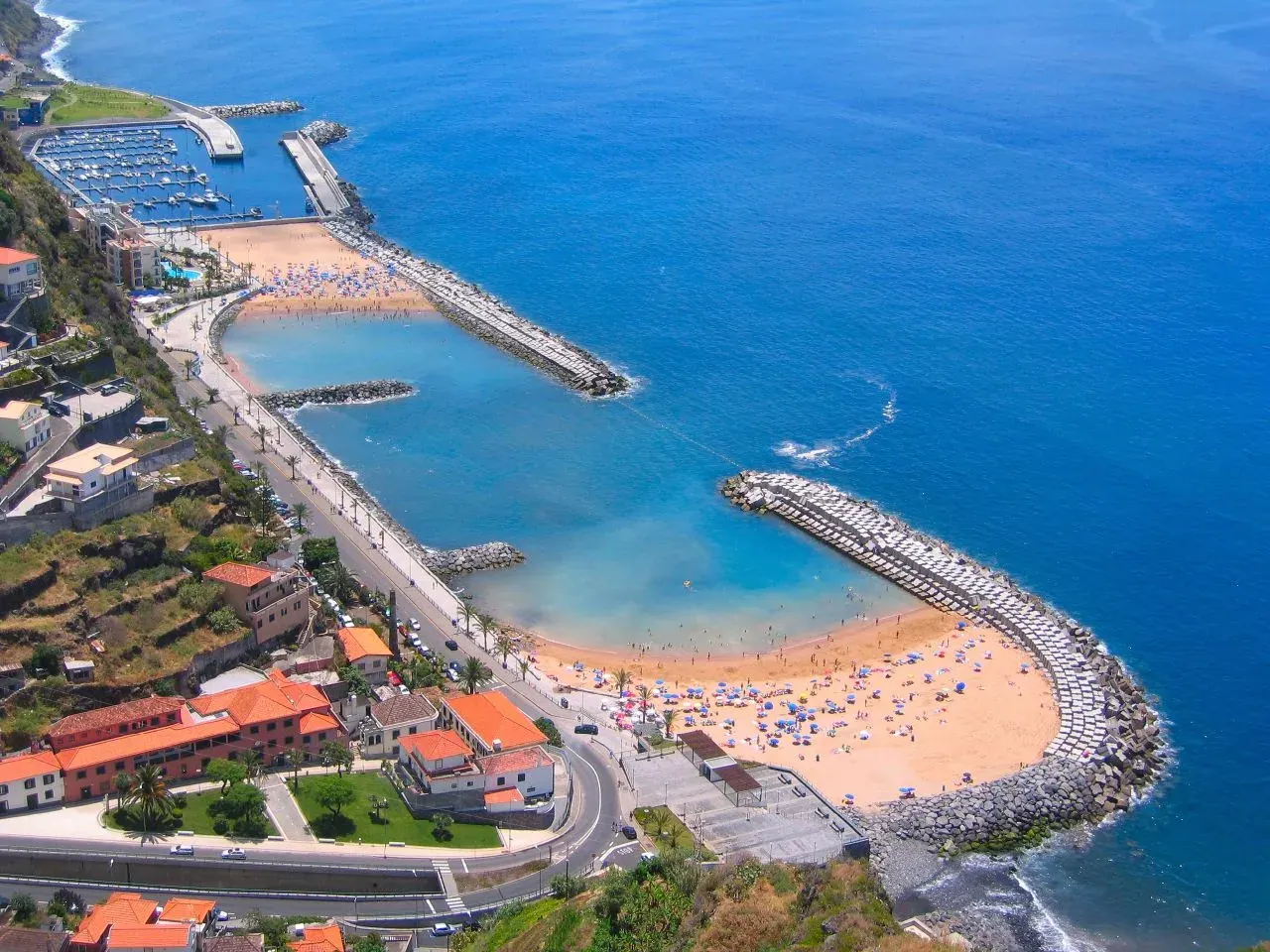 Calheta's golden-sand beach held between two breakwaters, with the marina and the Atlantic beyond